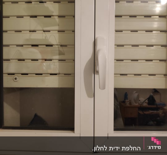 חלון עם תריסים סגורים וידית לבנה